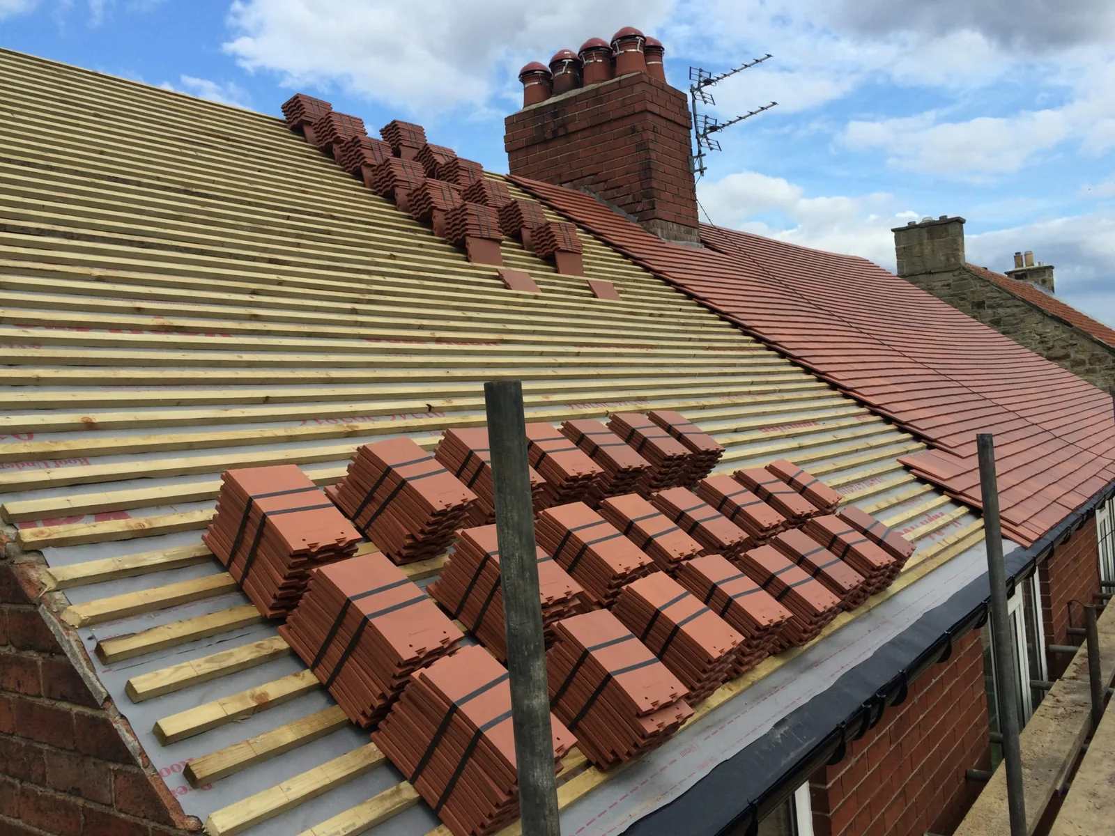 Clay roof tiles being installed over new battens and membrane on a North East home
